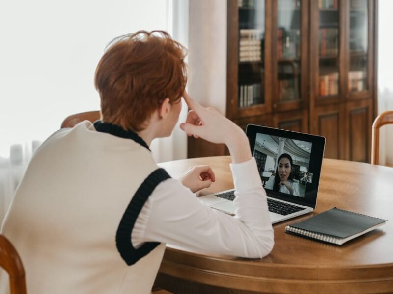 Person on a video call on a laptop using a webcam at a home desk