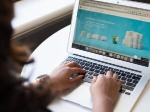 A woman browsing a website on a laptop by a window