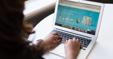 A woman browsing a website on a laptop by a window