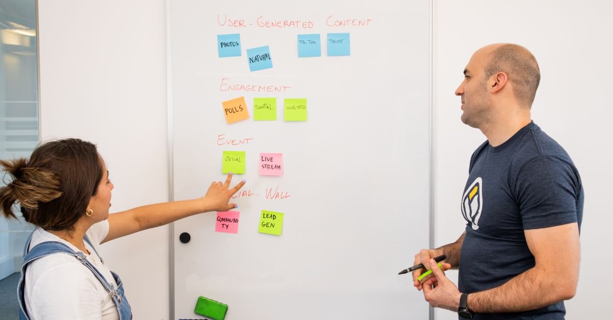 Two developers planning at a whiteboard with sticky notes