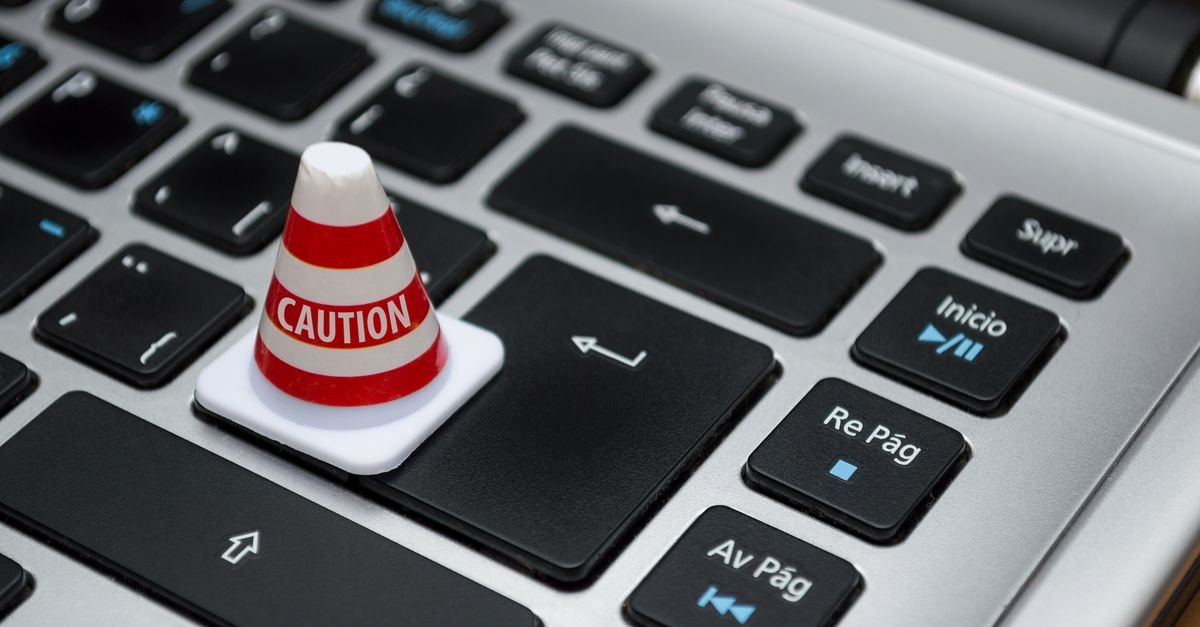 A miniature caution cone standing on a laptop keyboard