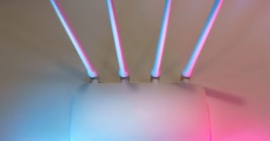 A wifi router glowing under neon pink and blue light