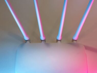 A wifi router glowing under neon pink and blue light