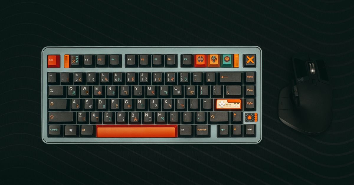 A mechanical keyboard with orange accent keys on a dark desk