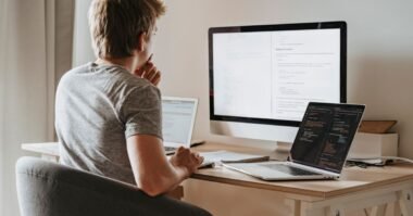 A developer working at a desk with two screens of code
