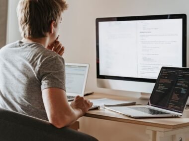 A developer working at a desk with two screens of code