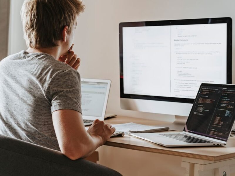 A developer working at a desk with two screens of code