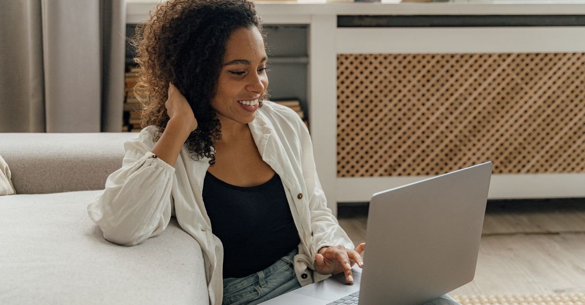 A woman using a laptop on a sofa at home