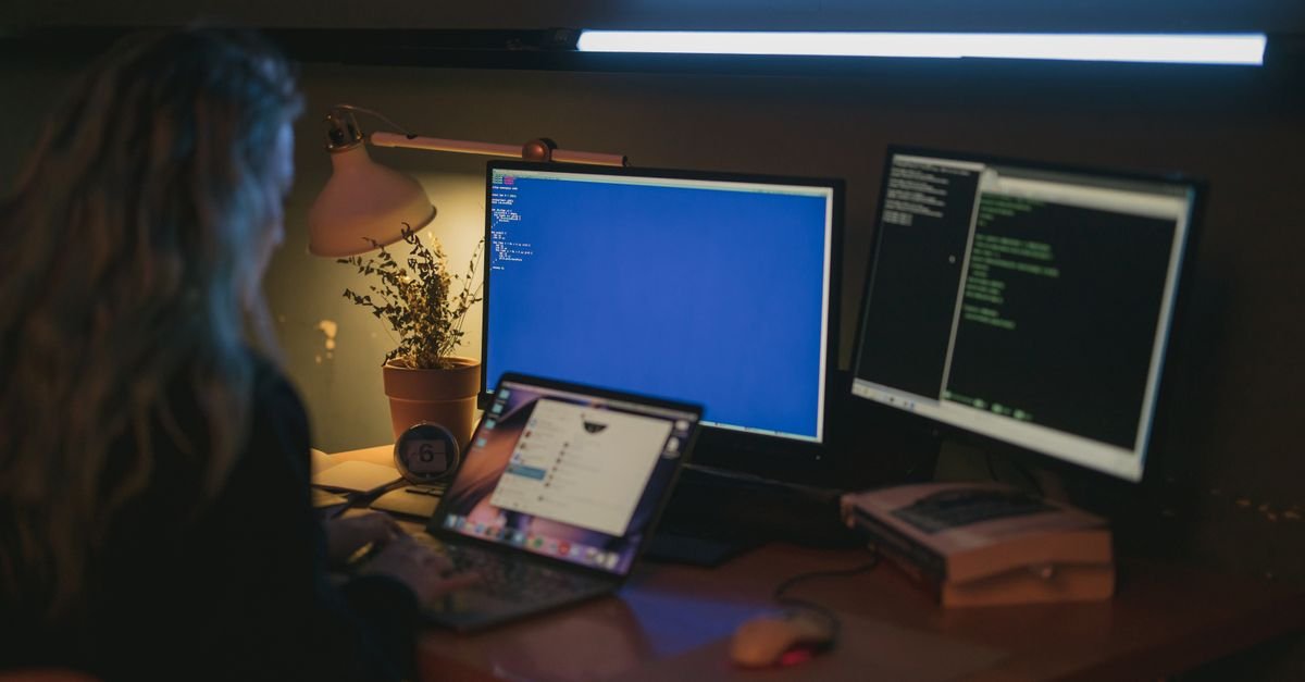 A developer at dual monitors in a dim room