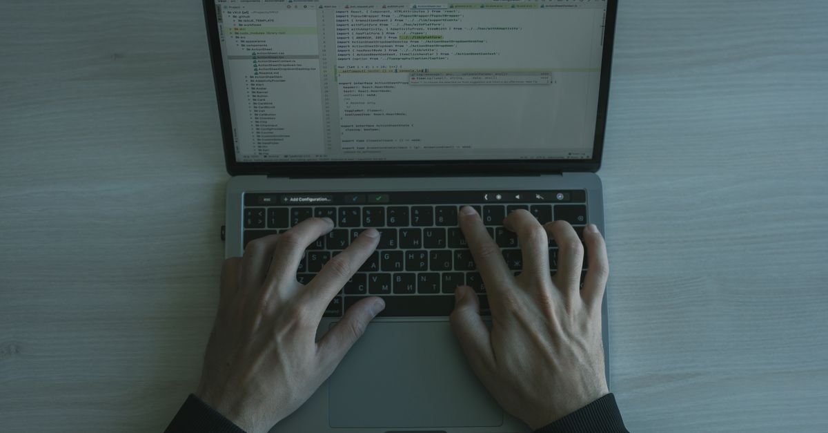 Hands typing code on a laptop keyboard