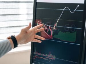 A hand pointing at a rising chart on a screen
