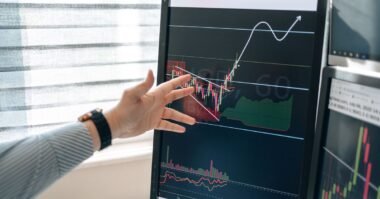 A hand pointing at a rising chart on a screen