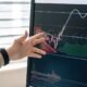 A hand pointing at a rising chart on a screen