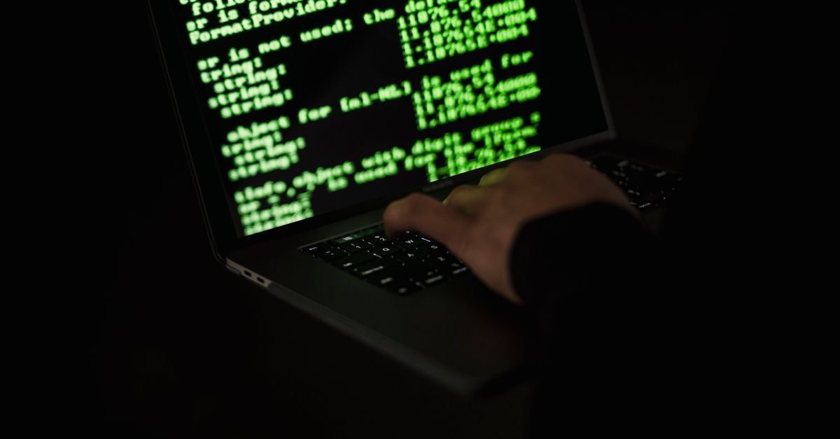 Lines of green code on a laptop screen in a dark room