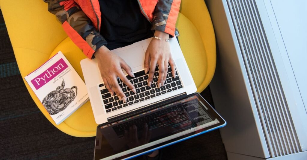 Developer working on a laptop with a reference book
